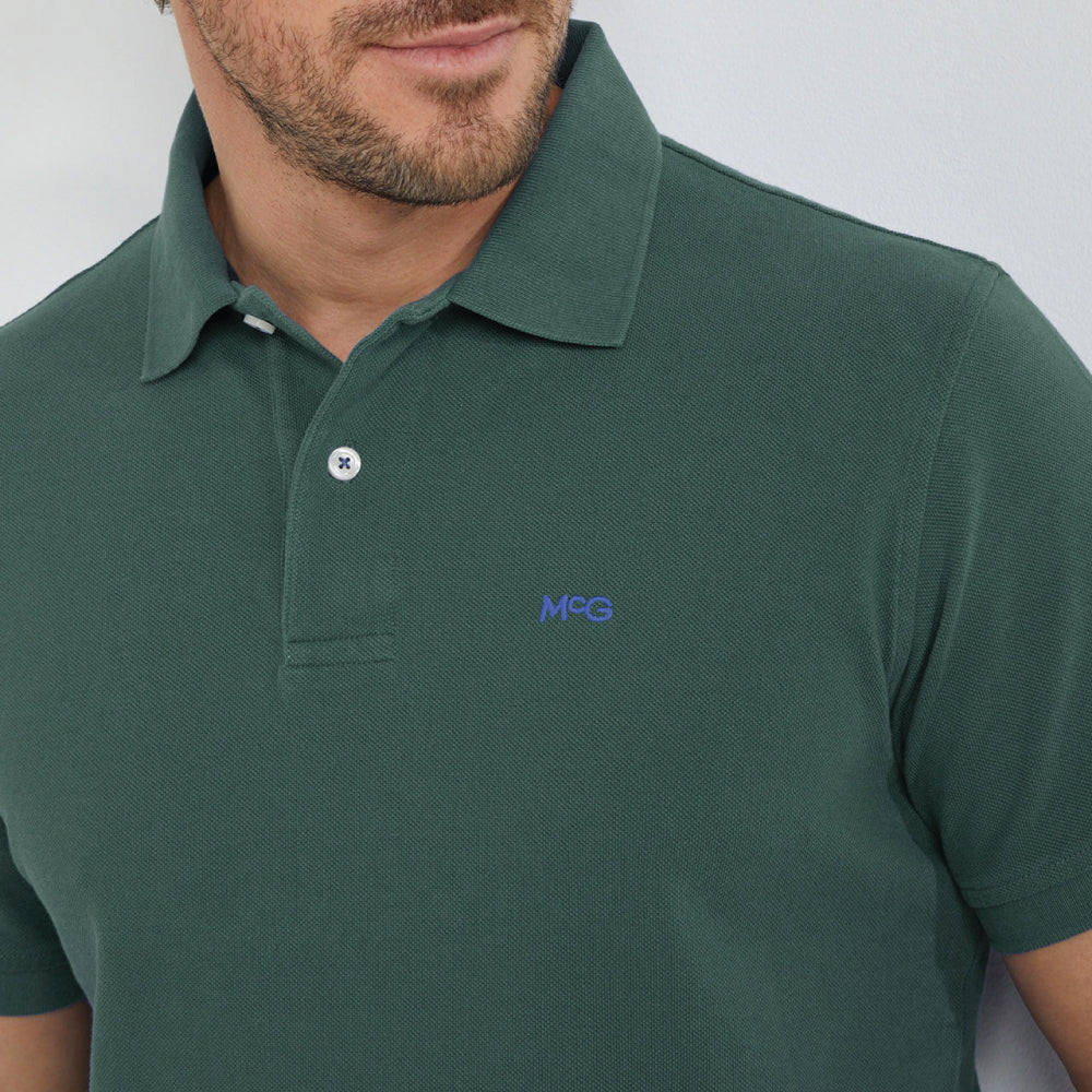 Model wearing a McGregor men's classic regular fit dark green polo shirt with a ribbed collar and short sleeves on a white background.