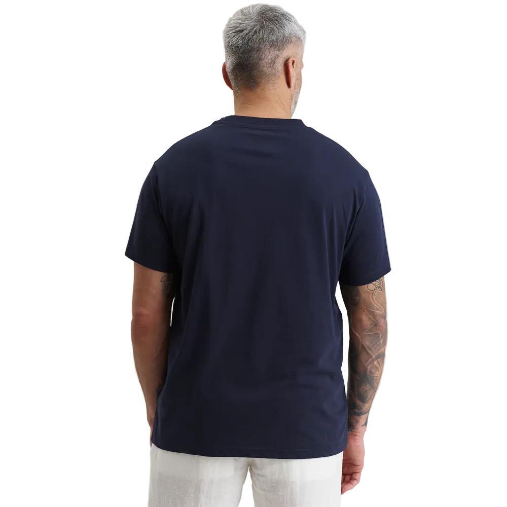 A man modeling a Bomboogie men's navy blue t-shirt against a plain white background. The short-sleeve crewneck shirt features a tonal, rectangular box logo with the text 'Bomboogie' printed across the chest, styled casually with off-white trousers.