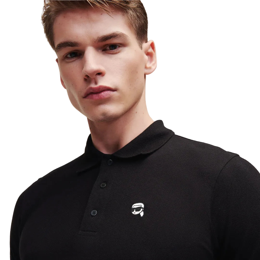 A side-profile view of a model looking away, wearing a fitted black short-sleeve Karl Lagerfeld polo shirt featuring a ribbed collar and a small embroidered chest logo.