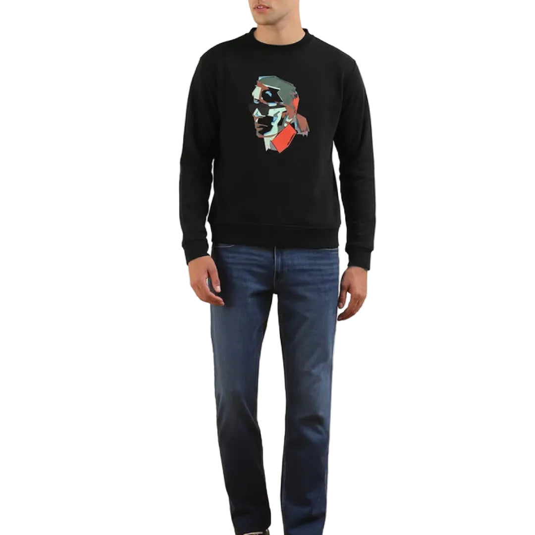 A male model wearing a black Karl Lagerfeld sweatshirt with a colorful graphic print on the front, paired with blue jeans.