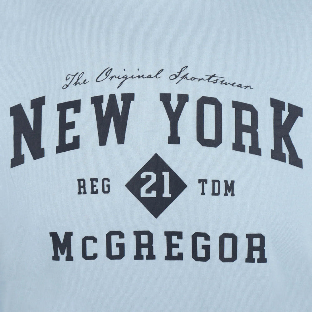Model wearing a McGregor men's light blue NY graphic crew neck T-shirt with a vintage New York print and short sleeves on a white background.
