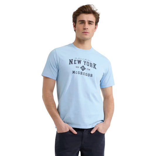 Model wearing a McGregor men's light blue NY graphic crew neck T-shirt with a vintage New York print and short sleeves on a white background.