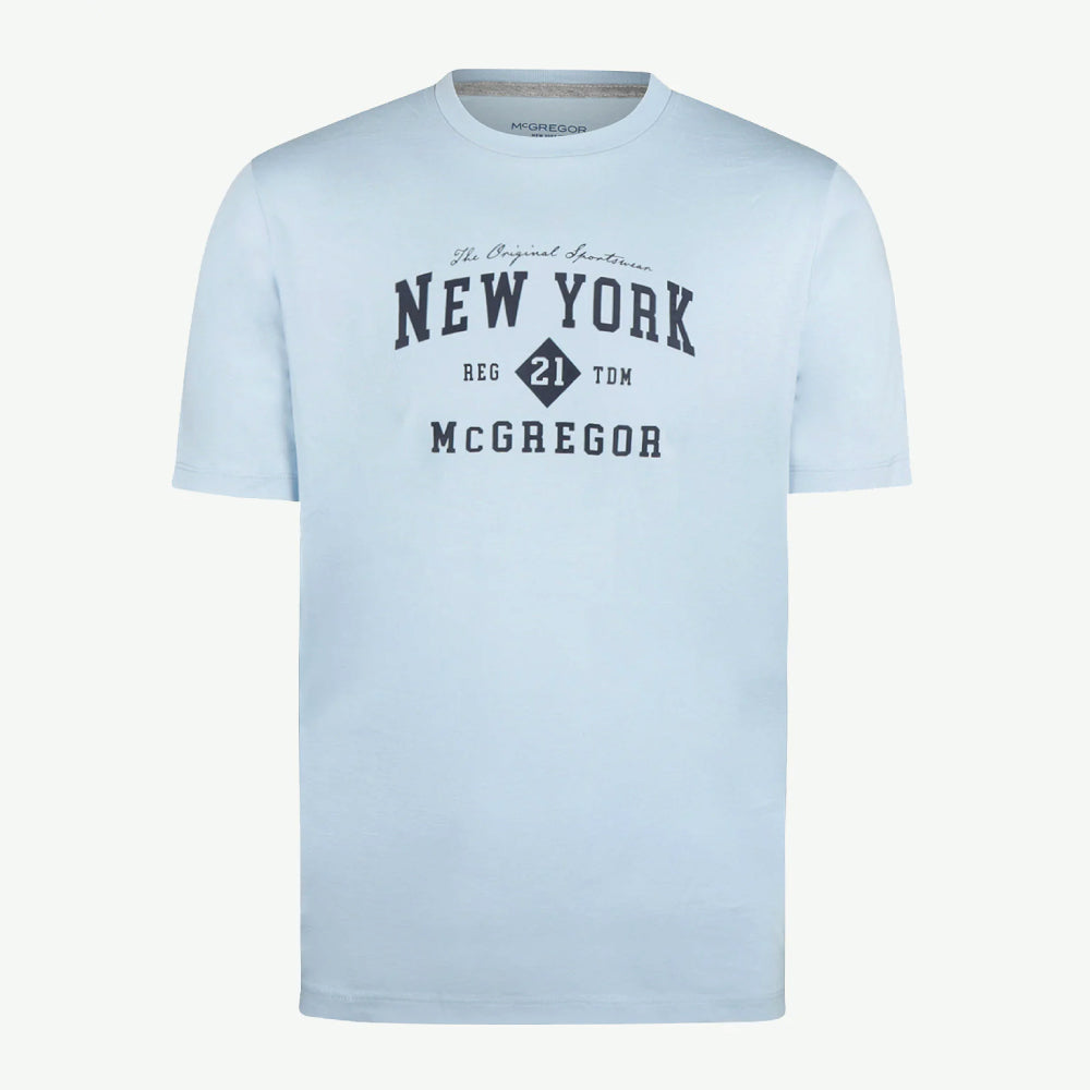 Model wearing a McGregor men's light blue NY graphic crew neck T-shirt with a vintage New York print and short sleeves on a white background.