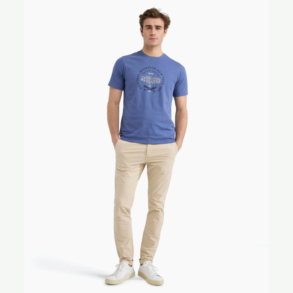 Model wearing a McGregor men's blue Original Print crew neck T-shirt with a vintage logo graphic and short sleeves on a white background.